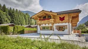 Una cabaña con balcón de madera, un paisaje de montañas y cielo despejado.