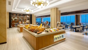 A modern hotel lobby with a buffet area, large windows, and a view of the city. - Aston Gresik Hotel & Conference Center (Gresik)