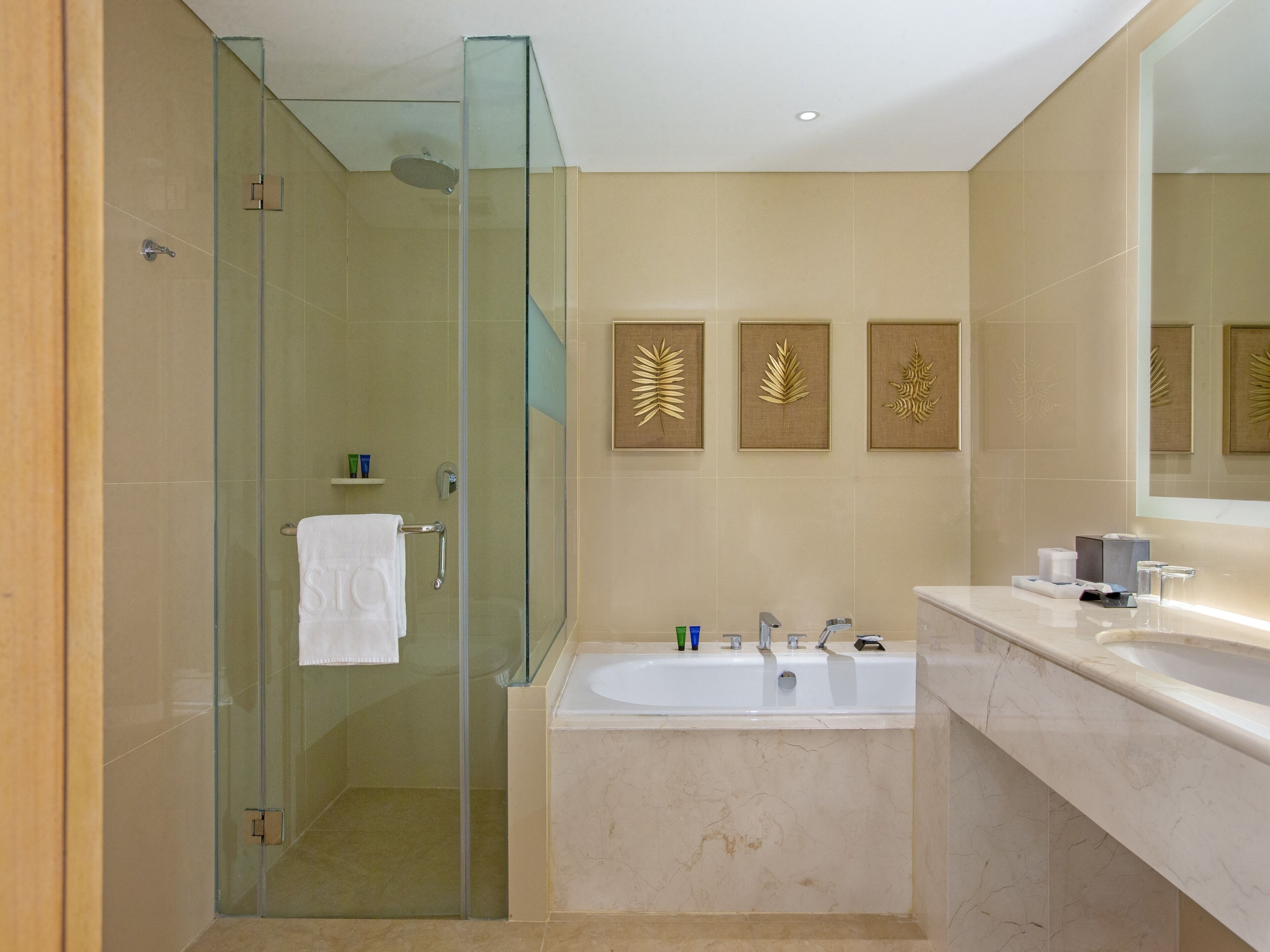 Un baño moderno con ducha envuelta en vidrio, una bañera grande y un tocador con espejo.