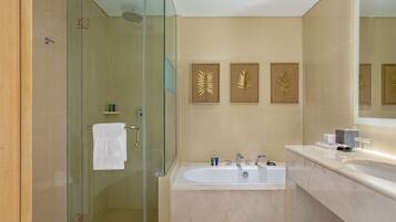 Un baño moderno con ducha envuelta en vidrio, una bañera grande y un tocador con espejo.