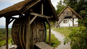 A rustic wooden structure with a thatched roof and a wooden barrel.