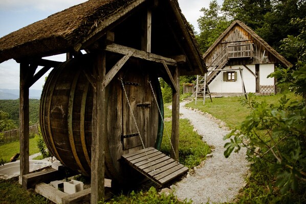 A rustic wooden structure with a thatched roof and a wooden barrel. - Vineyard cottage Škatlar 2 (Otočec)