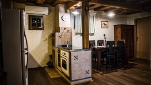 A compact kitchen with a refrigerator, stove, and dining area with chairs.