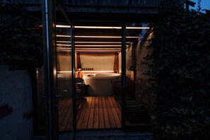 Un espace bien-être avec un jacuzzi et une terrasse en bois.