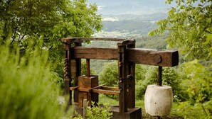 Una estructura de madera rústica con una amplia base de piedra, rodeada de exuberante vegetación y una vista panorámica al fondo.