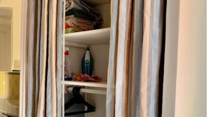 A closet with shelves containing folded clothes, a hanger, and a bottle. - Rental small 3 Pieces Historic Center (Menton)