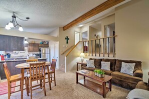 A living room with a wooden coffee table, a brown sofa, and a dining area with wooden chairs and a table.