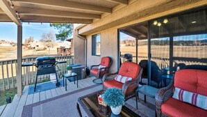 A covered outdoor patio with wicker furniture, a grill, and a view of a parking lot. - Condo on Golf Course: 2 Mi to Grindstone Lake! (Ruidoso)