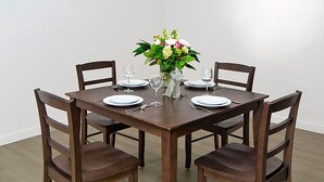 Et spisebord dækket til fire personer med stole, en vase med blomster og vinglas.