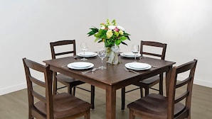 A dining table set for four with chairs, a vase of flowers, and wine glasses. - Stay Alfred Cultural District (Pittsburgh)