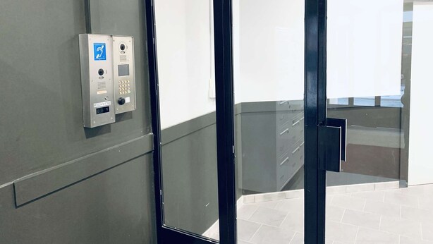 En moderne elevator med kontrolpanel, der viser et Wi-Fi-symbol, et kamera og et tastefelt.