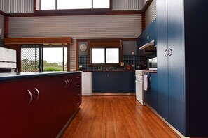 A modern kitchen with wooden cabinets, a built-in oven, and a large window.