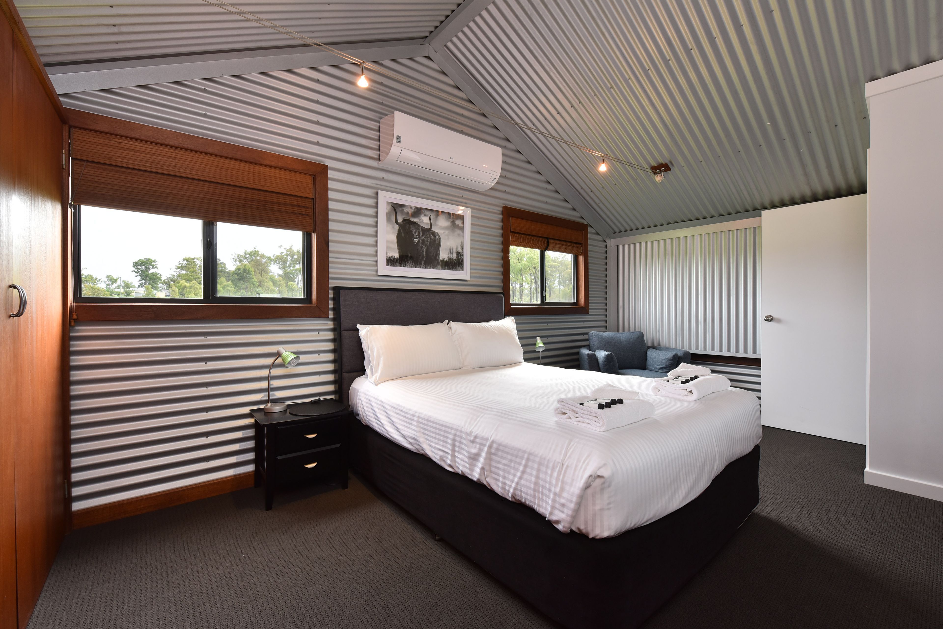 A modern bedroom with a large bed, bedside tables, a desk, and a chair.