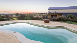A swimming pool with a curved edge, a large planter, and a building with a flat roof in the background.