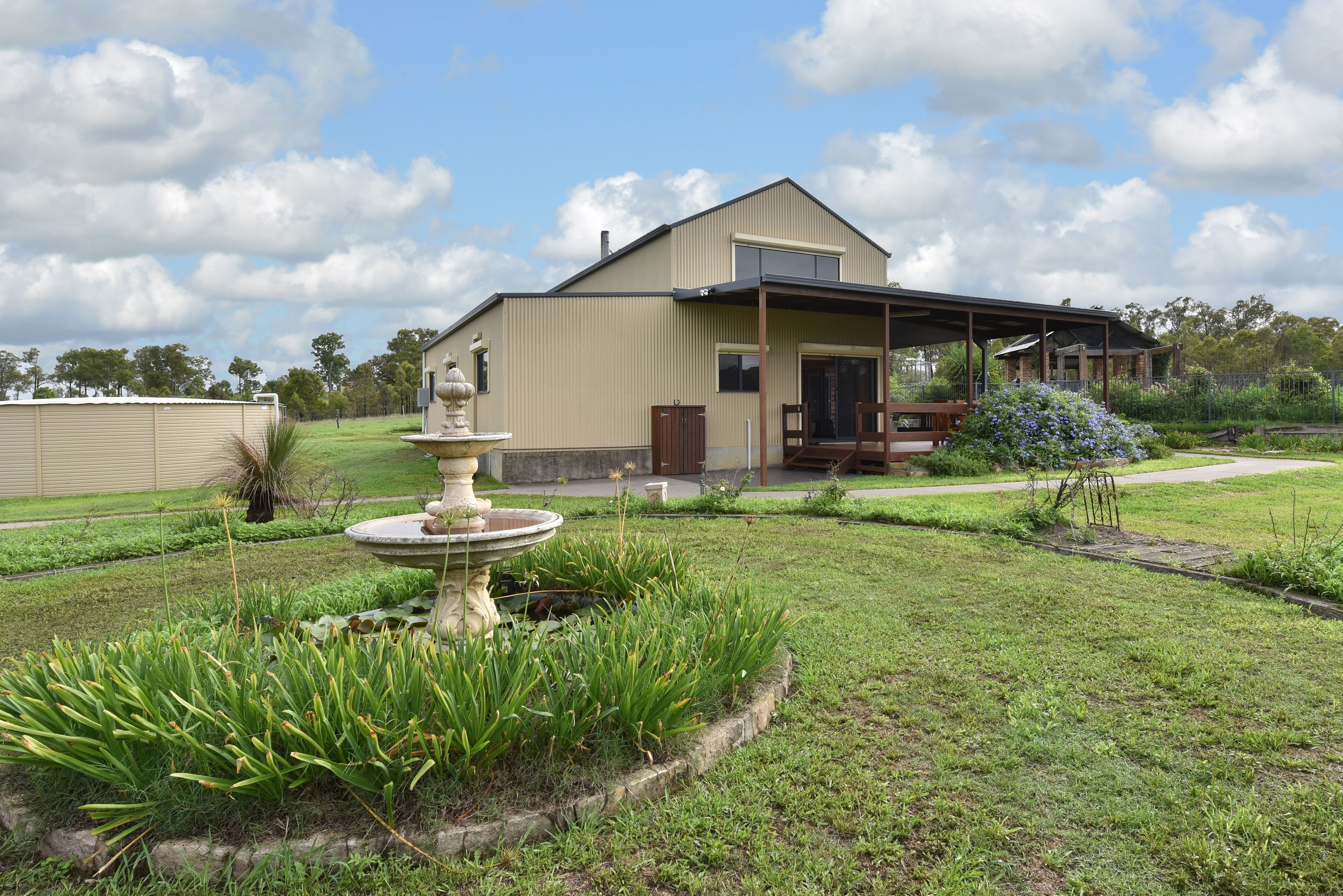 A house with a covered porch, a garden with a fountain, and a lawn.