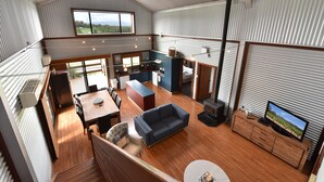 A spacious living area with a kitchen, dining table, sofa, and a TV.