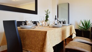 Un coin repas avec une table dressée pour quatre personnes, comprenant des assiettes, des verres et des couverts.
