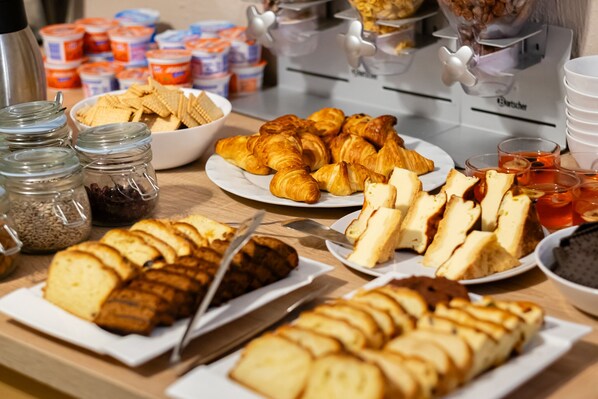 A buffet with various food items including pastries, sandwiches, and spreads. - Hotel Maximum (Kraków)
