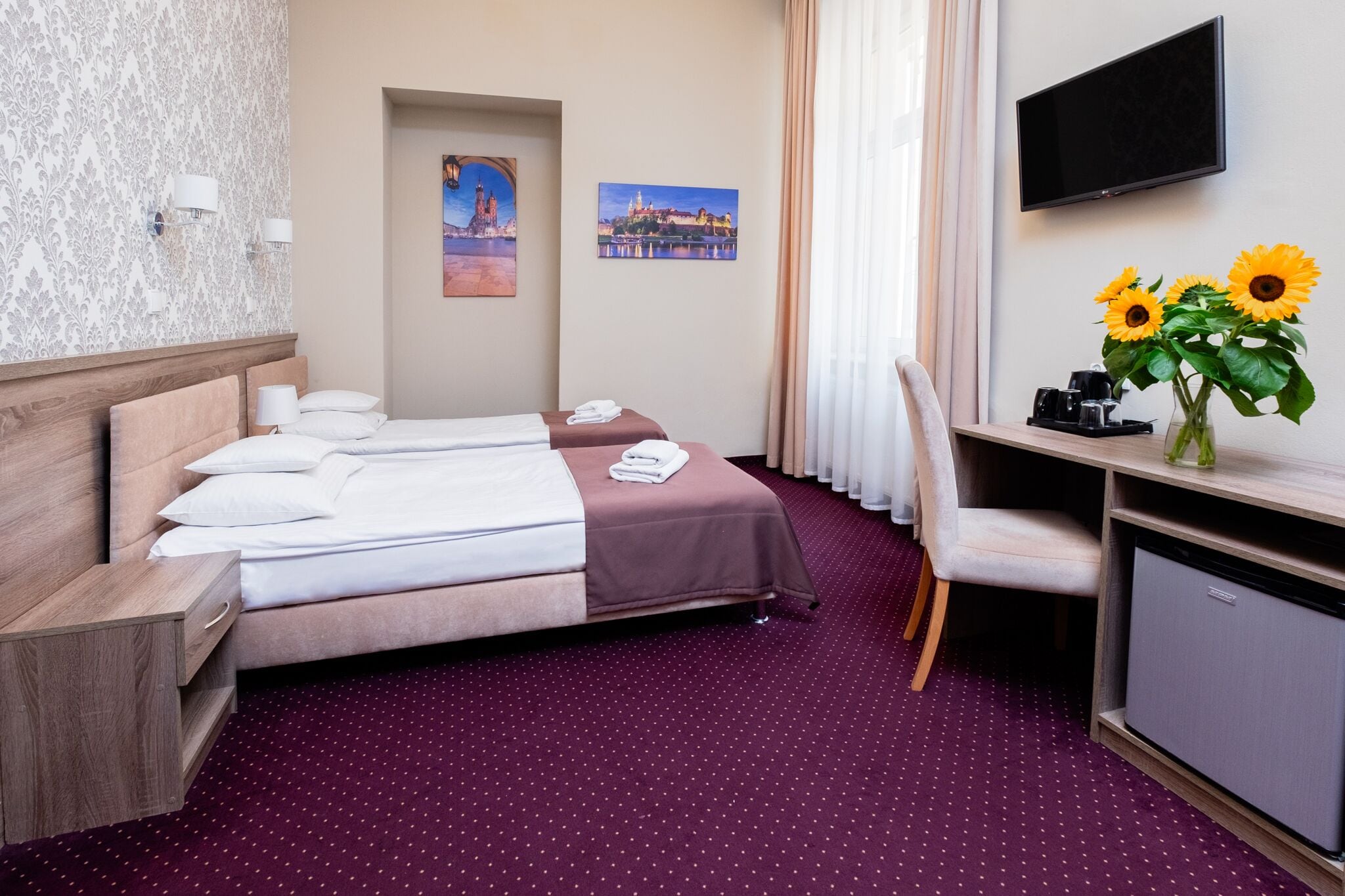 A hotel room with a bed, a desk, a television, and a wall-mounted TV.