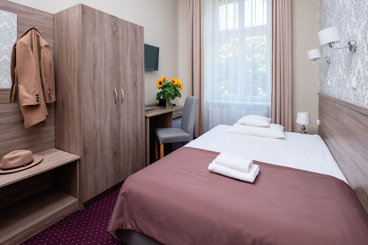 Una habitación de hotel con cama, escritorio, silla, televisor y armario.