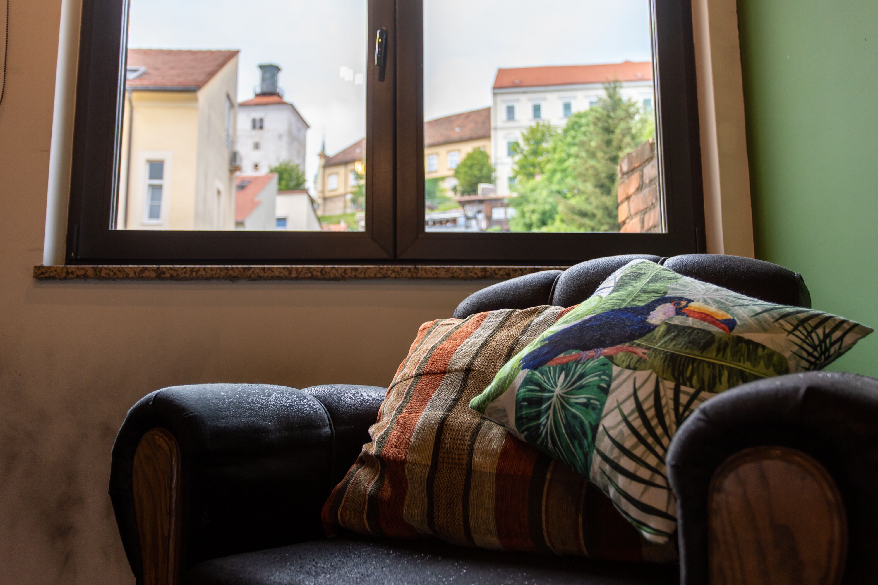 A chair with a patterned cushion and a window with a view of buildings.