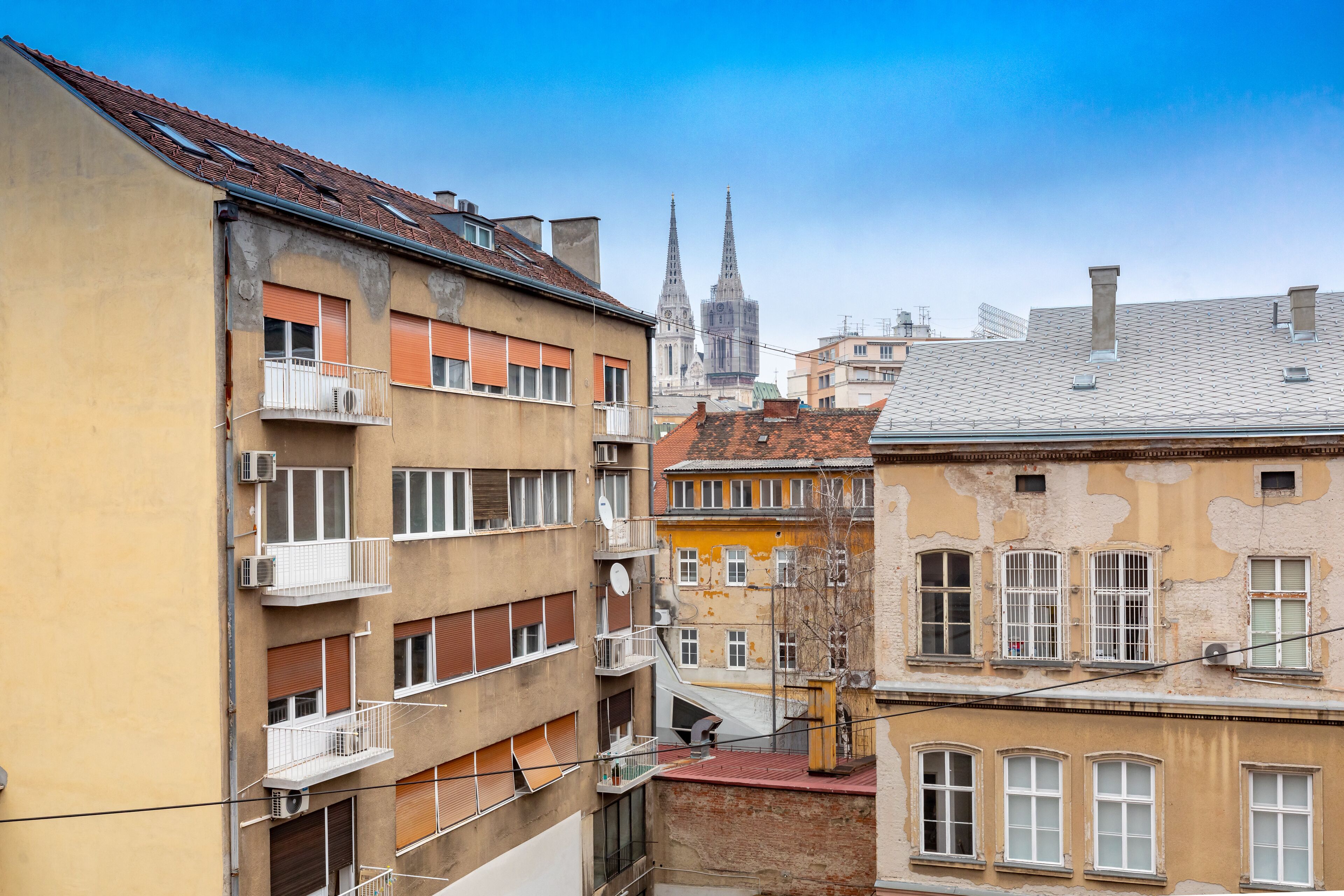 Un immeuble à plusieurs étages, doté de balcons, avec en arrière-plan le clocher d’une église.