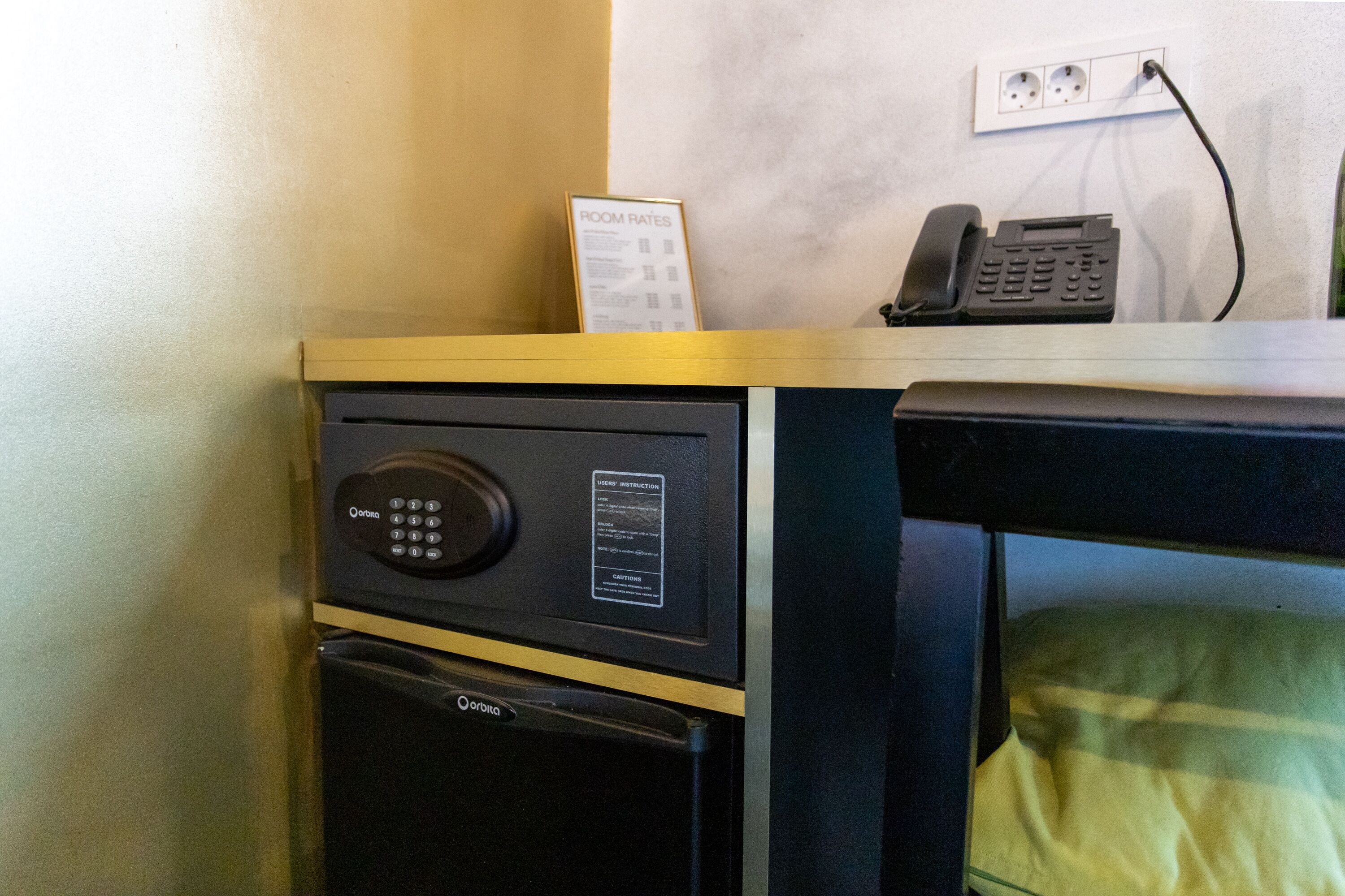 Un minibar con un teléfono y un cartel que indica las tarifas de la habitación.