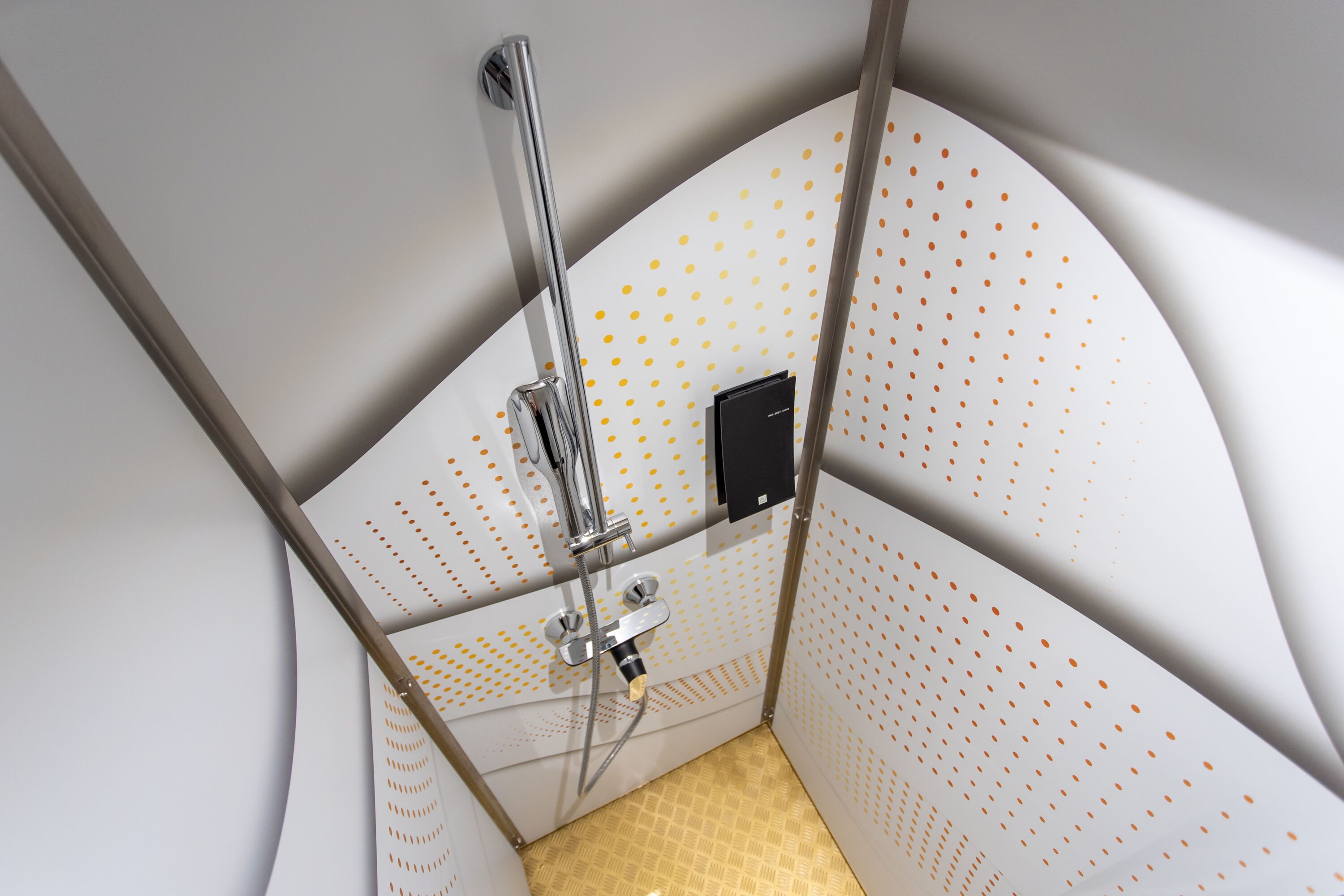 Un box de ducha moderno con diseño curvo, panel de control y ducha de mano.