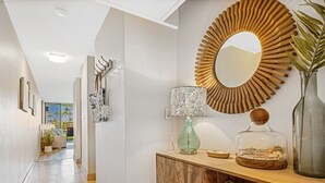 Un couloir avec une armoire en bois, un miroir, une lampe et des objets décoratifs.