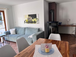 Une pièce comprenant un canapé, une table à manger avec un set de table, une bouilloire et une cheminée.
