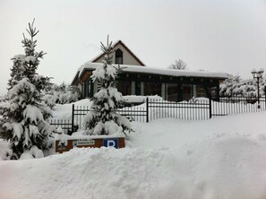 A building with a snow-covered roof and a fenced parking area.