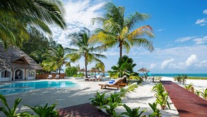 A poolside area with lounge chairs and a wooden deck leading to the beach. - Amani Boutique Hotel - Small Luxury Hotels of the World (Paje)