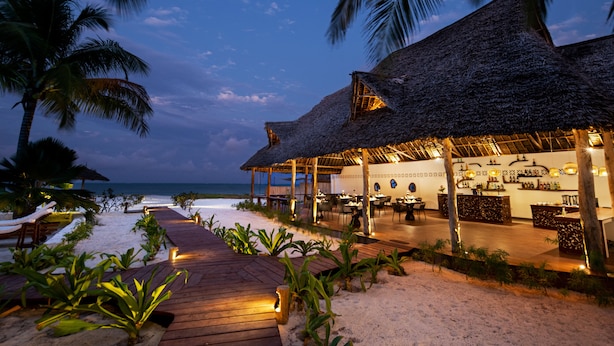 A beachside resort with a thatched-roof bar and dining area, wooden deck, and palm trees. - Amani Boutique Hotel - Small Luxury Hotels of the World (Paje)