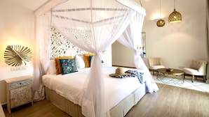 A bedroom with a four-poster bed, a bedside table, a chair, and a small round table. - Amani Boutique Hotel - Small Luxury Hotels of the World (Paje)