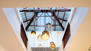 A spacious hallway with a wooden reception desk, wicker chairs, and hanging pendant lights. - Amani Boutique Hotel - Small Luxury Hotels of the World (Paje)