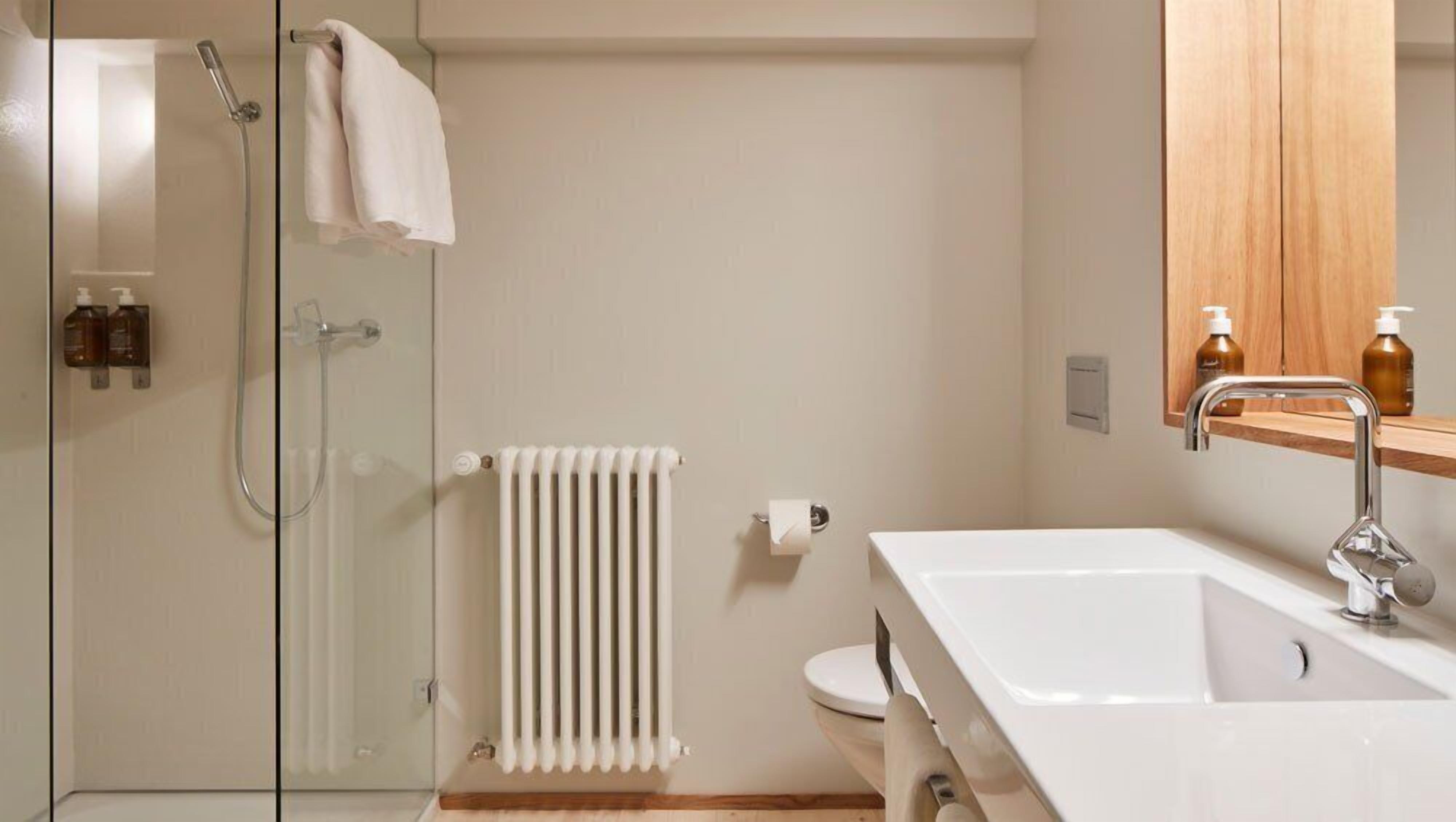 Une salle de bain moderne avec une douche à parois de verre, un lavabo blanc et un meuble-lavabo en bois.