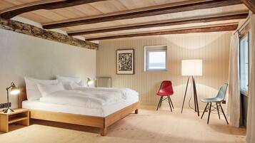 Un dormitorio con una cama de madera, una silla roja, una silla azul, una lámpara de pie y un radiador.