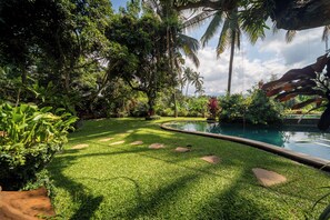 Ein üppiger Garten mit Pool, umgeben von tropischen Pflanzen und Palmen.