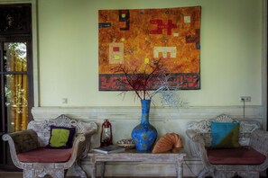 A room with two ornate sofas, a blue vase with decorative elements, and a large abstract painting on the wall. - Wonderful luxury hideaway surrounded by nature (Seririt)