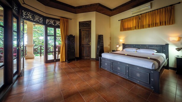 Un dormitorio con una cama grande, un armario de madera, una puerta y vistas al exterior.