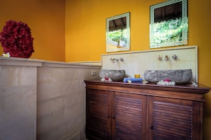 A bathroom with a wooden vanity, two mirrors, and a decorative red coral.