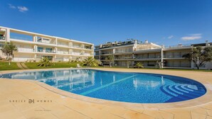 Un hotel moderno con piscina, varios balcones y un jardín bien cuidado.