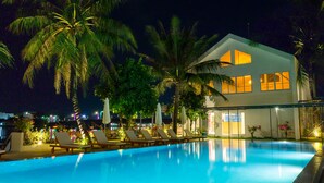 Un hôtel moderne doté d’une piscine, de chaises longues et de palmiers.