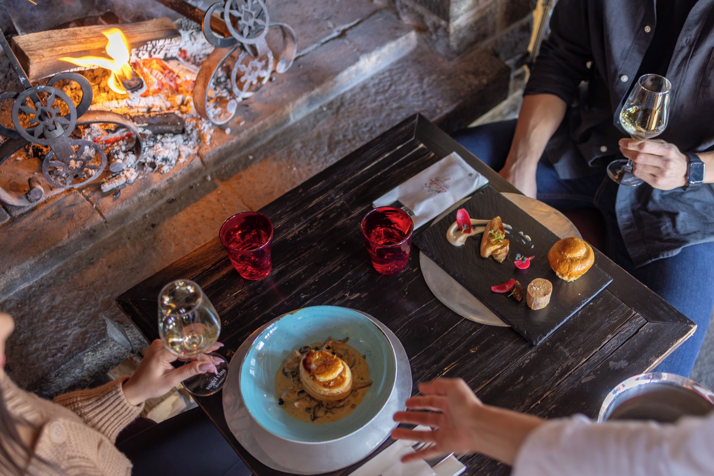 A table with a candlelit ambiance, a bowl of food, and red glasses.