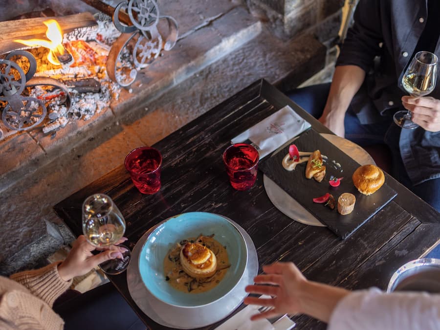 A table with a candlelit ambiance, a bowl of food, and red glasses.