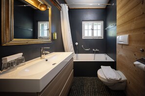 Une salle de bain moderne avec un grand miroir, une baignoire et des toilettes.