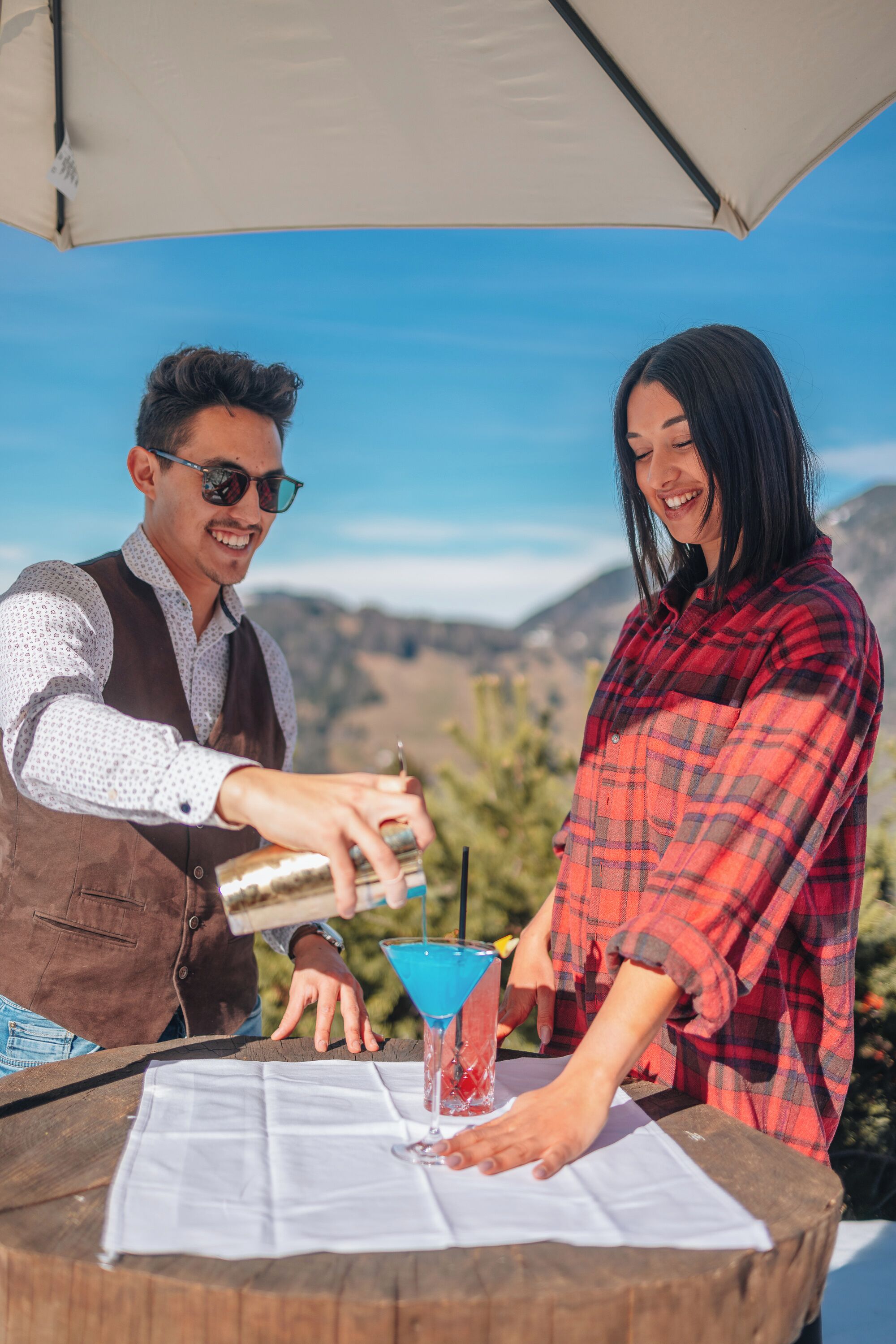 A man and a woman at an outdoor table with a drink and a martini glass.