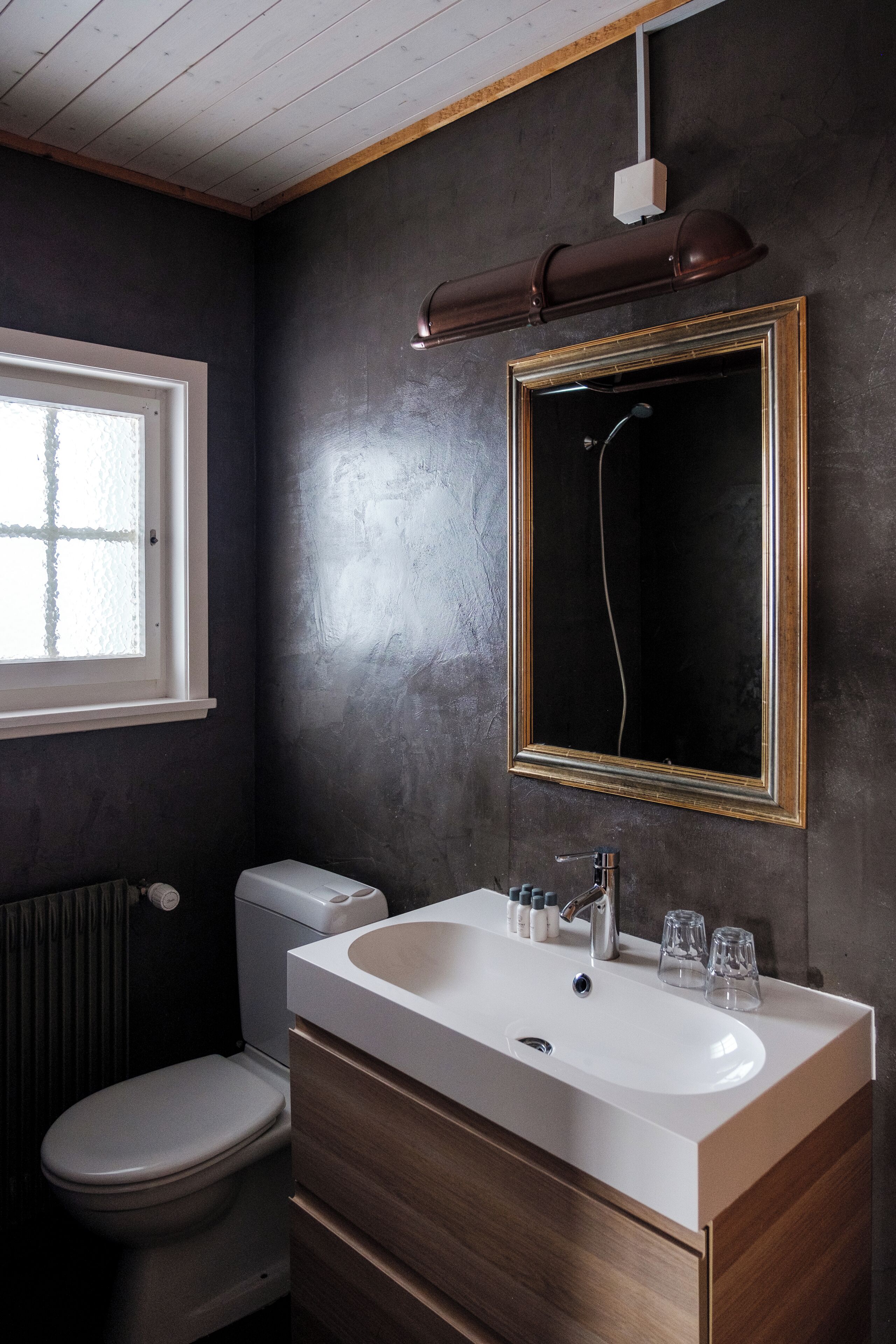 Une salle de bain moderne avec un lavabo blanc, un meuble-lavabo en bois, des toilettes et un grand miroir.