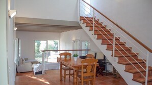 Un vaste espace de vie comprenant un escalier en bois, une table à manger avec des chaises et un canapé.
