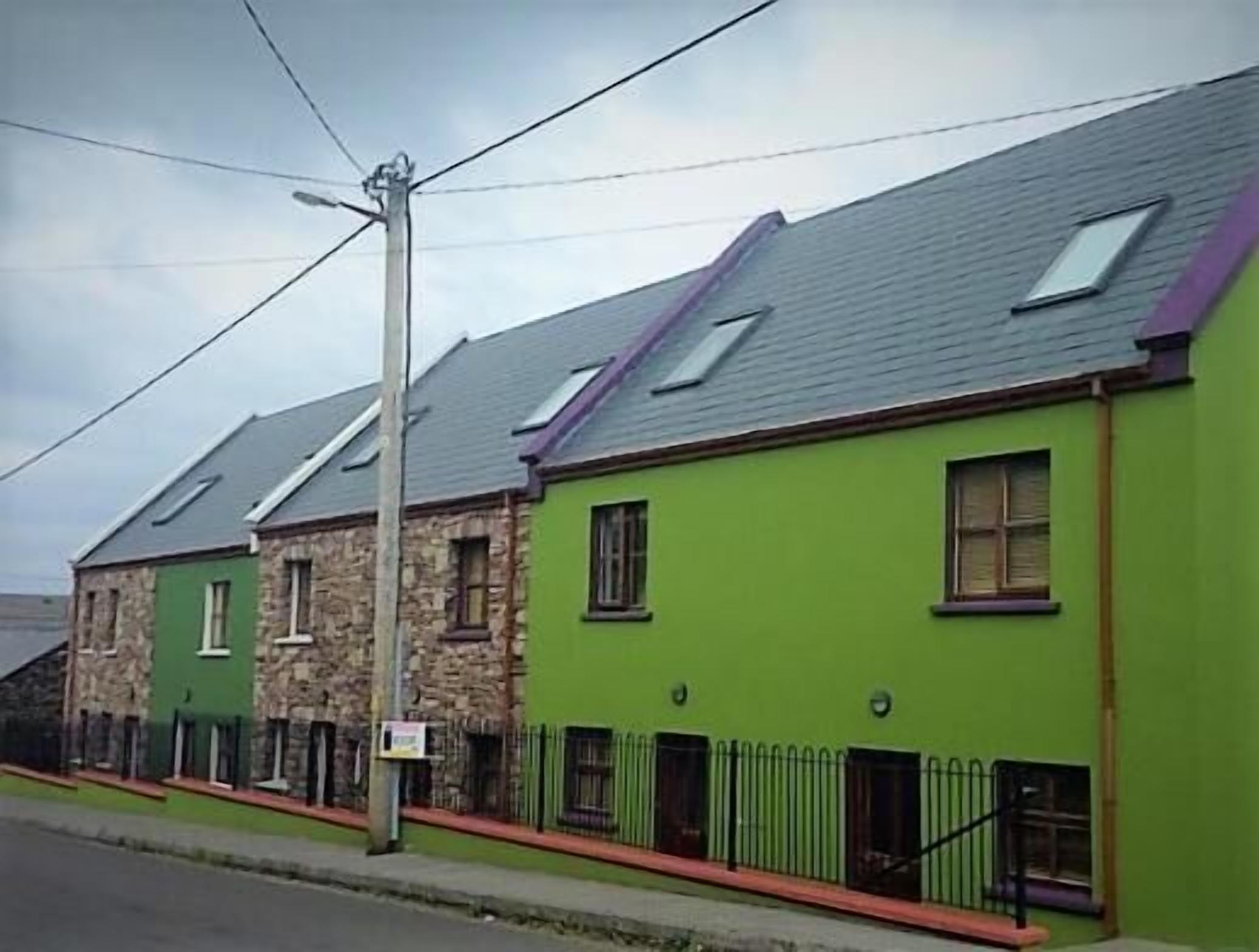 A row of terraced houses with a green facade and stone detailing.